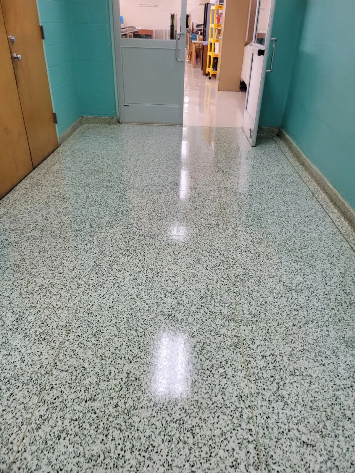 A polished terrazzo corridor in an institutional building, reflecting the ceiling lights after refinishing