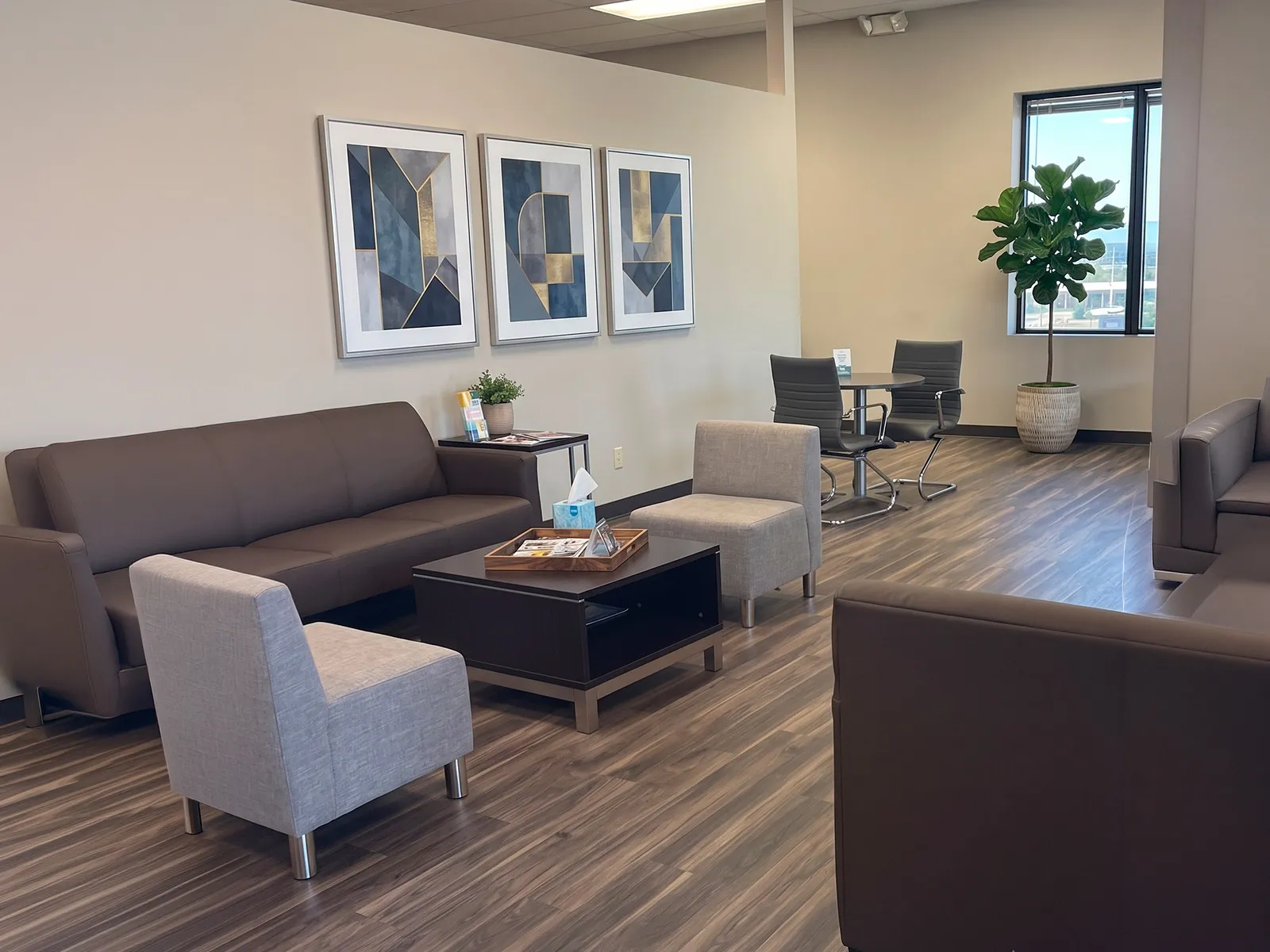 The furnished common lounge of a managed building — sofas, armchairs and a seating area over hard flooring